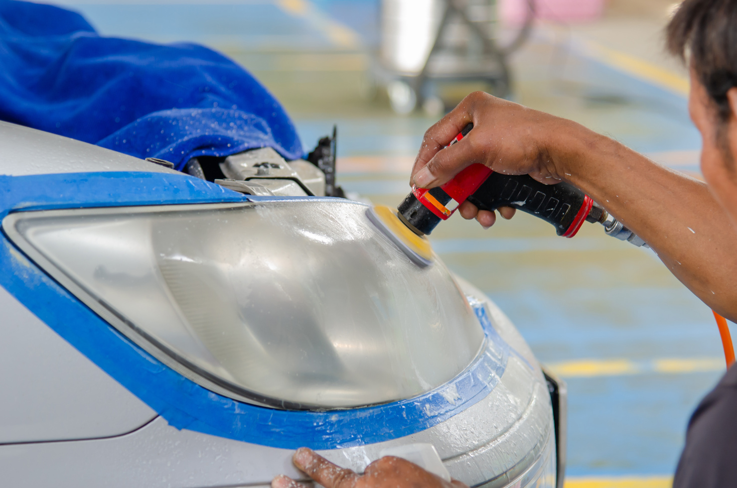 Worker Polishing the Headlight of a Car  